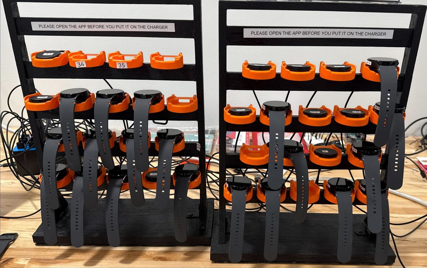 Custom 3D-printed charging dock holding numbered smartwatches in the classroom